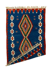 Alfombra kilim con una esquina doblada, mostrando la parte trasera del tejido artesanal y los flecos en color natural.