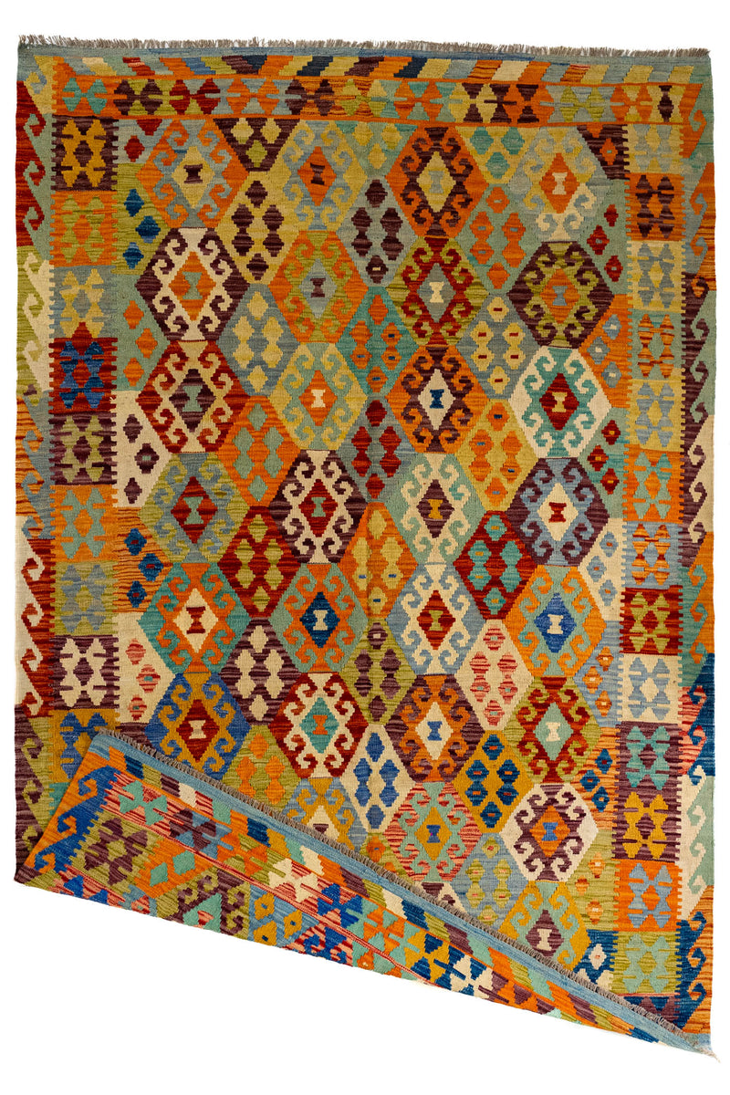 Vista general de la alfombra kilim con una esquina doblada, revelando el reverso de la pieza y destacando su reversibilidad artesanal.