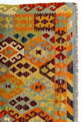 Primer plano del borde superior izquierdo que muestra una variedad de motivos étnicos y colores intensos con detalles minuciosamente tejidos.