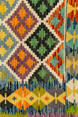 Detalle del borde inferior derecho con rombos de colores contrastantes, incluyendo verde, naranja y azul, sobre fondo claro.