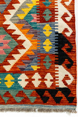 Detalle lateral derecho que destaca la transición de patrones y colores, incluyendo rombos en azul, amarillo y rosado, con bordes en zigzag.