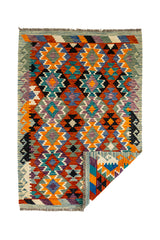 Vista general de la alfombra kilim con una esquina doblada, revelando el reverso de su tejido plano y la calidad artesanal.