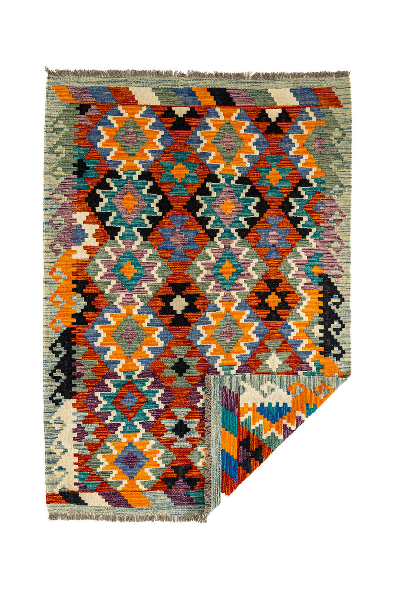 Vista general de la alfombra kilim con una esquina doblada, revelando el reverso de su tejido plano y la calidad artesanal.