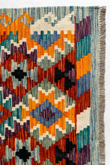 Detalle superior derecho de la alfombra, destacando los motivos en zigzag y las transiciones cromáticas vibrantes.