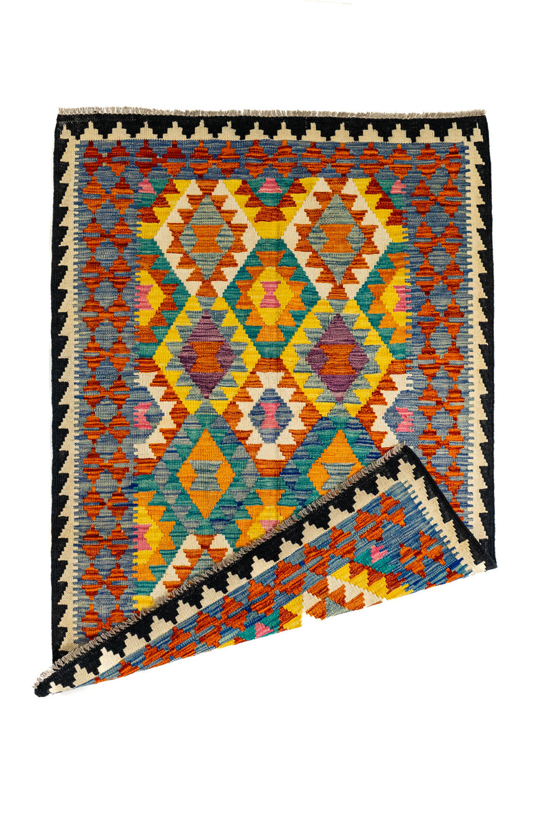 Alfombra kilim con una esquina doblada, mostrando la parte posterior del tejido artesanal y su diseño reversible.