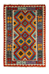 Vista superior completa de una alfombra kilim de patrón geométrico con diamantes en tonos anaranjado, azul, amarillo, verde y morado.