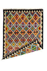 Alfombra kilim doblada en una esquina, mostrando el reverso tejido con los mismos patrones geométricos.