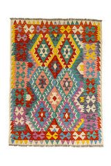 Vista completa de una alfombra kilim con patrones de diamantes en tonos rosado y bordes coloridos, destacando verdes, morado y amarillos.