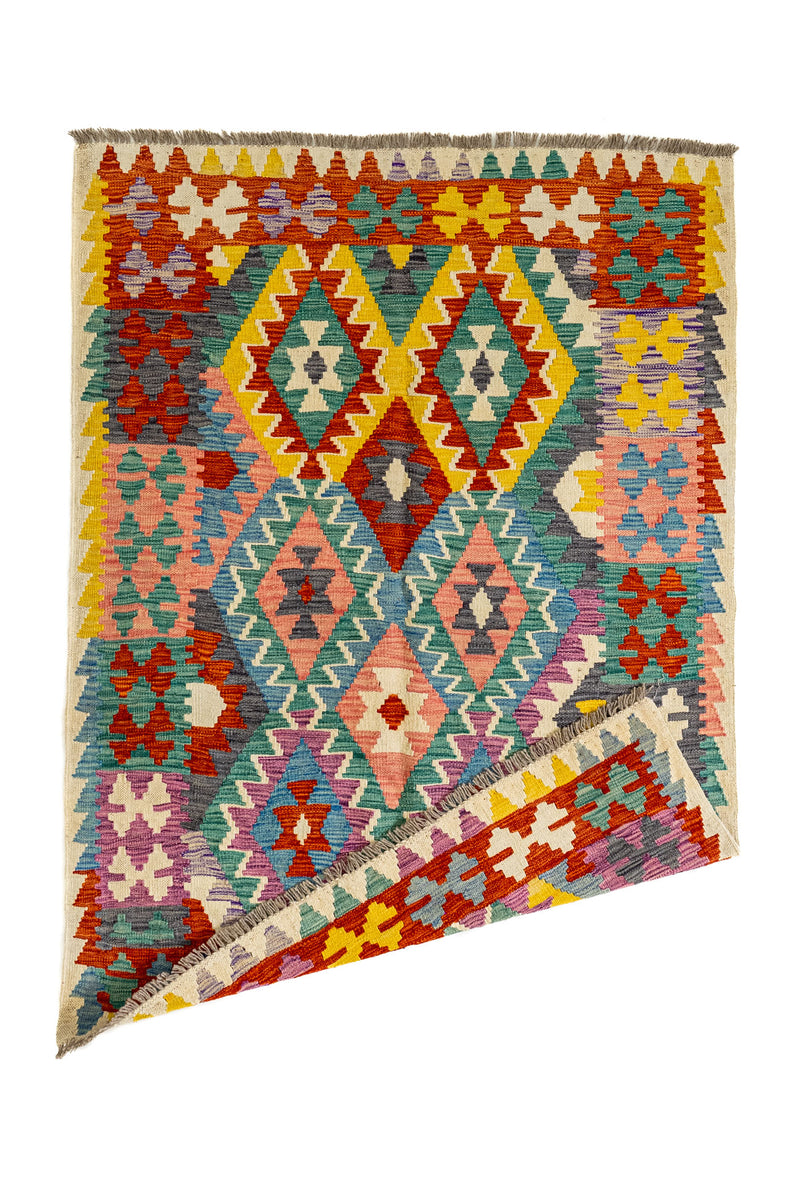 Alfombra kilim con una esquina doblada que muestra el reverso del tejido artesanal con los mismos motivos geométricos.