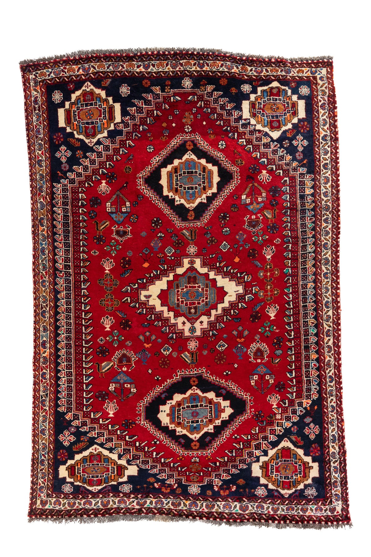 Vista frontal de alfombra estilo Kazak con fondo rojo intenso, medallones geométricos en beige y detalles en azul marino.