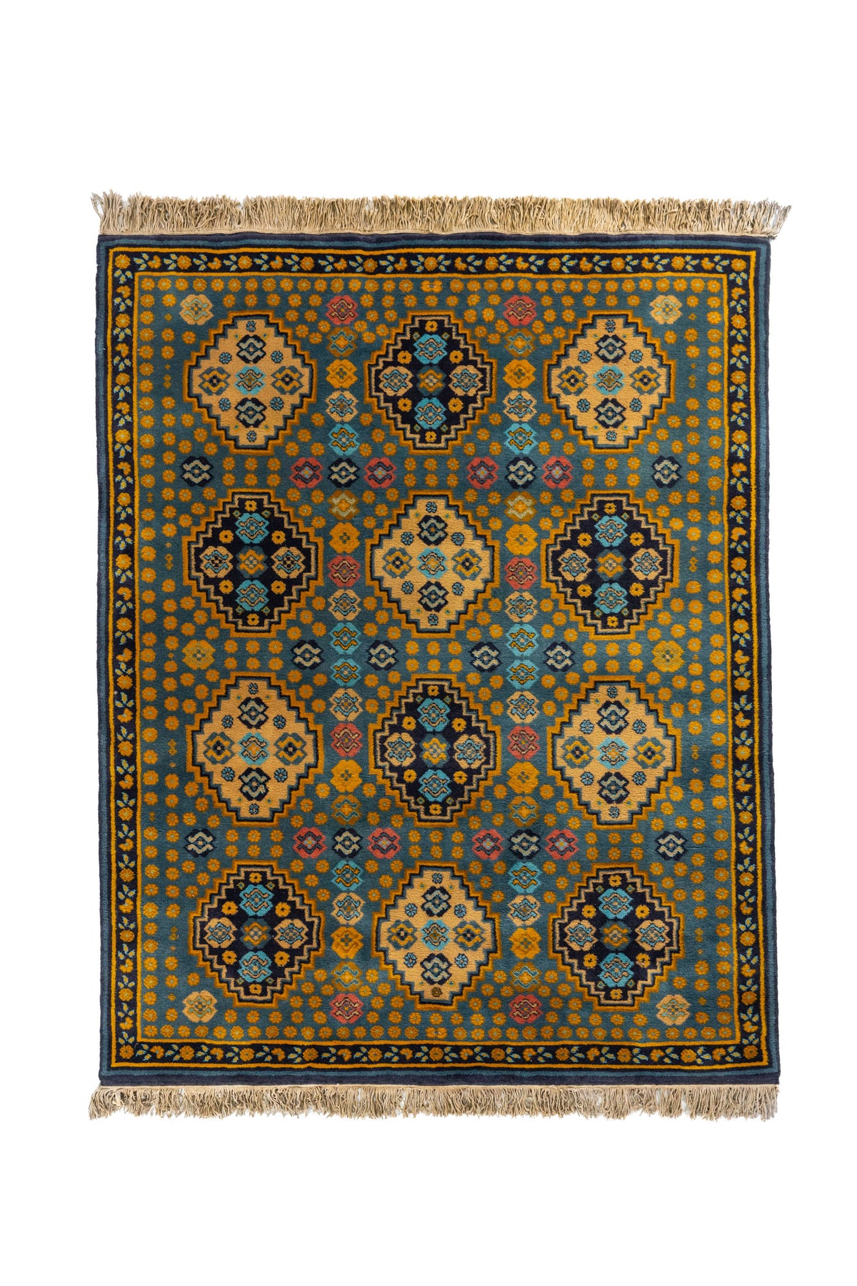 Alfombra de estilo geométrico tradicional con fondo azul suave, medallones escalonados en tonos beige y azul oscuro, y detalles en dorado, celeste y rosa.