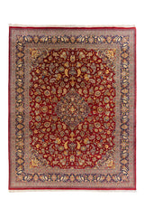 Alfombra oriental clásica en tonos rojo profundo y azul marino con diseño floral simétrico y medallón central sobre fondo claro.