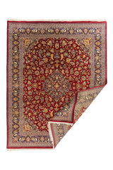 Alfombra clásica roja y azul con esquina doblada que muestra el reverso, detalles del tejido y flecos en color marfil.