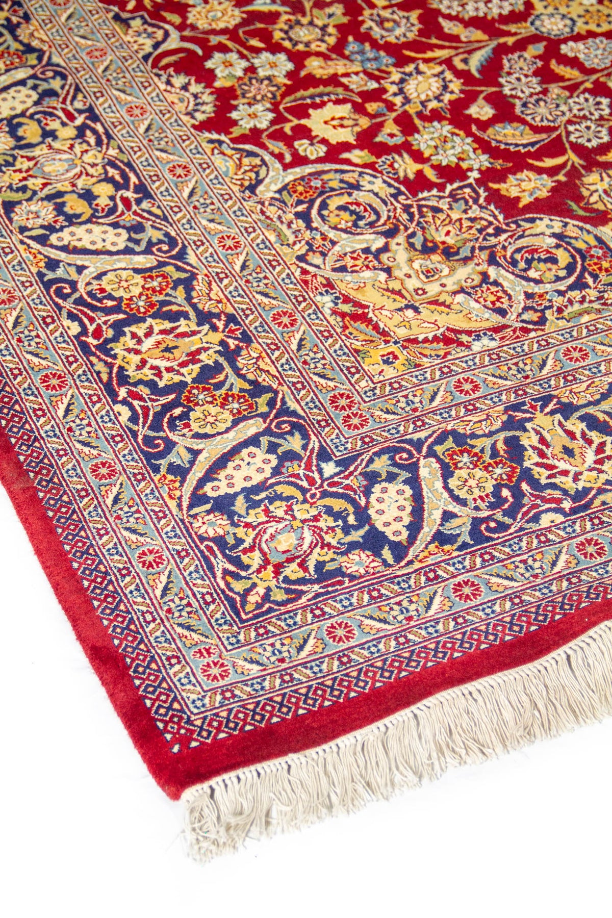 Detalle del diseño floral de alfombra oriental con fondo rojo vibrante, franja azul y líneas ornamentales finamente tejidas.