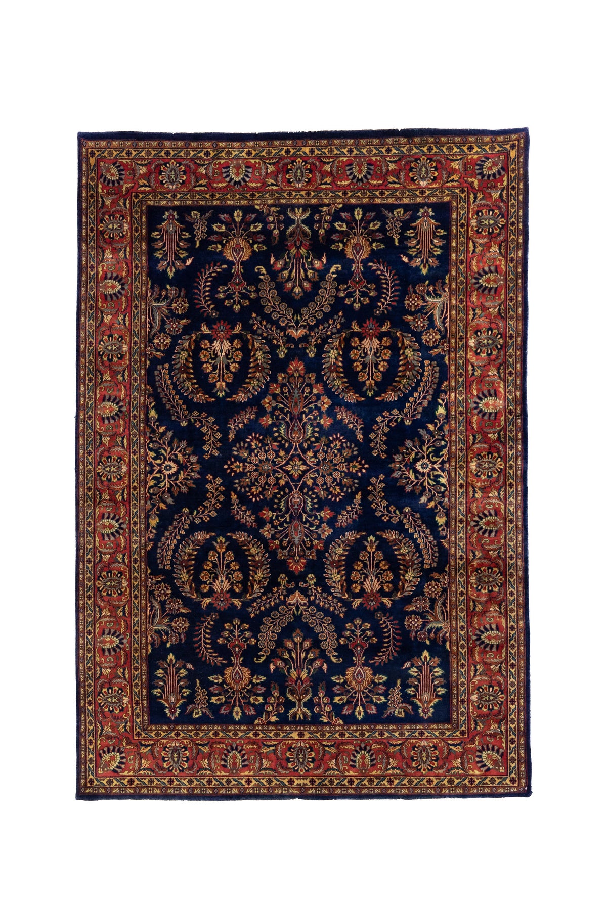 Alfombra clásica oriental con fondo azul profundo, motivos florales simétricos y guarda roja decorativa.