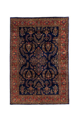Alfombra clásica oriental con fondo azul profundo, motivos florales simétricos y guarda roja decorativa.