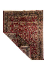 Alfombra roja de estilo persa con una esquina levantada que deja ver el reverso y el espesor del tejido.