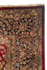 Primer plano de esquina de alfombra oriental con flores pequeñas, marco decorativo y flecos beige.