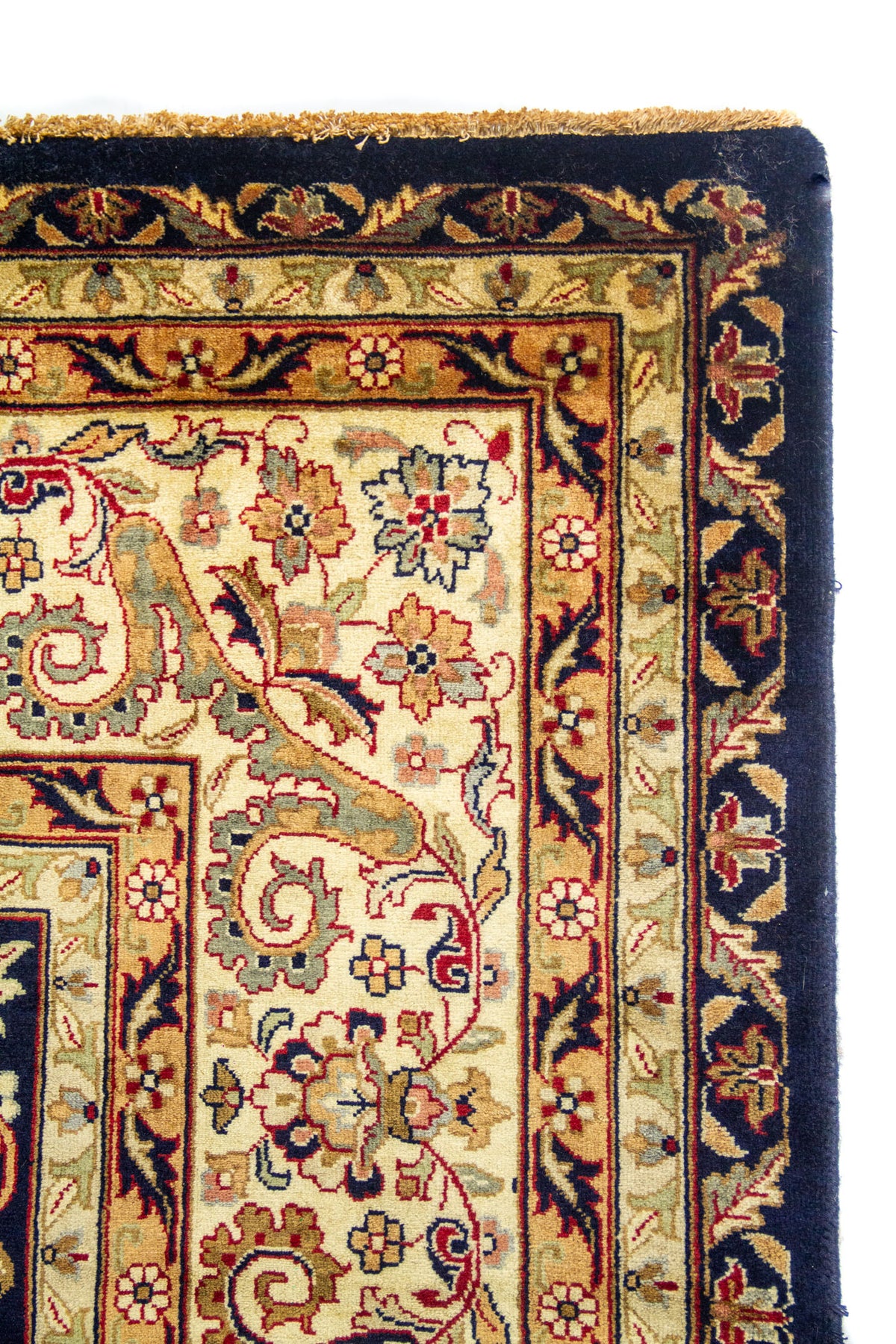 Primer plano de borde de alfombra clásica azul con guarda clara, flores ornamentales y acabado artesanal