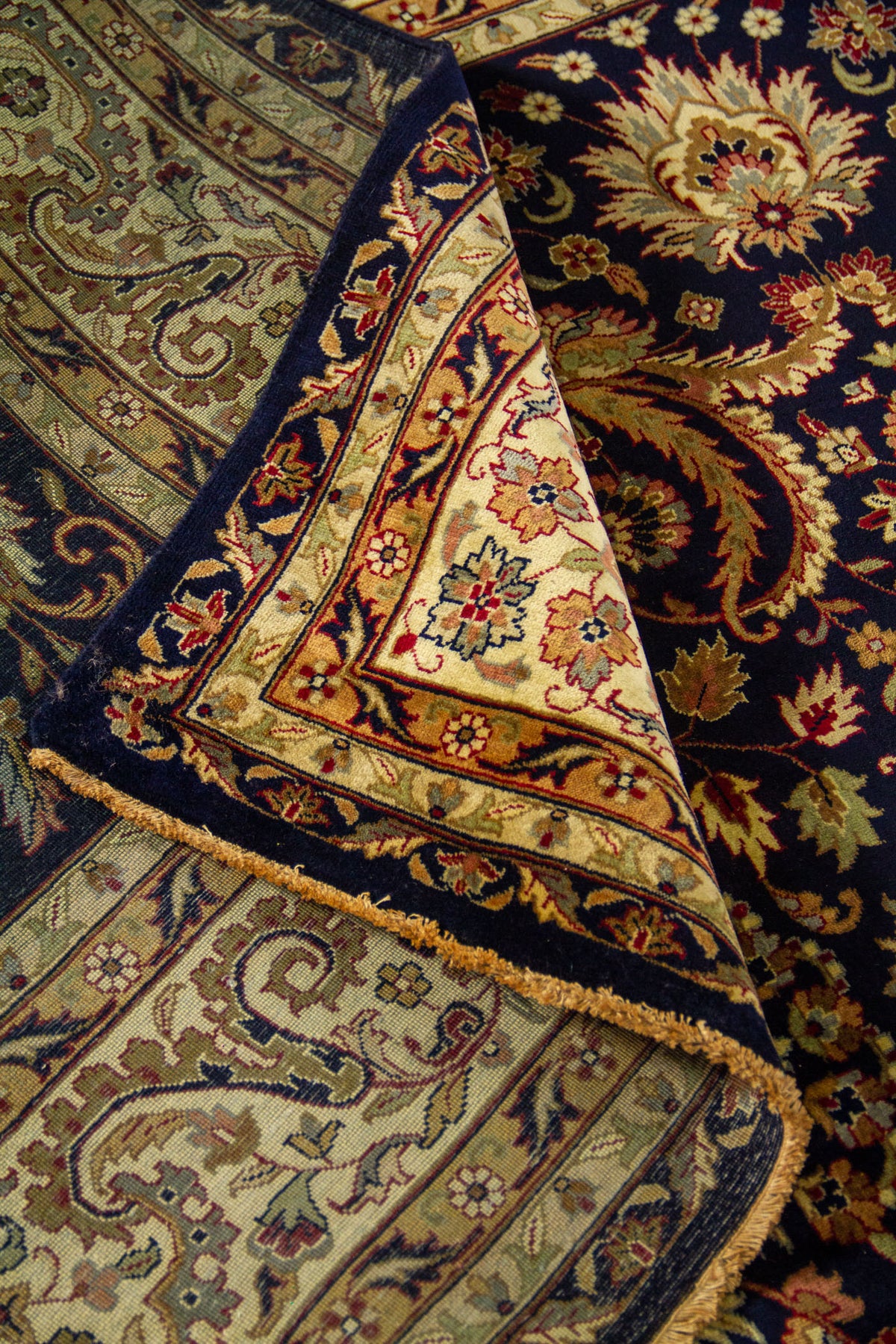 Alfombra azul marino doblada en detalle que resalta la textura, flexibilidad y riqueza del diseño floral