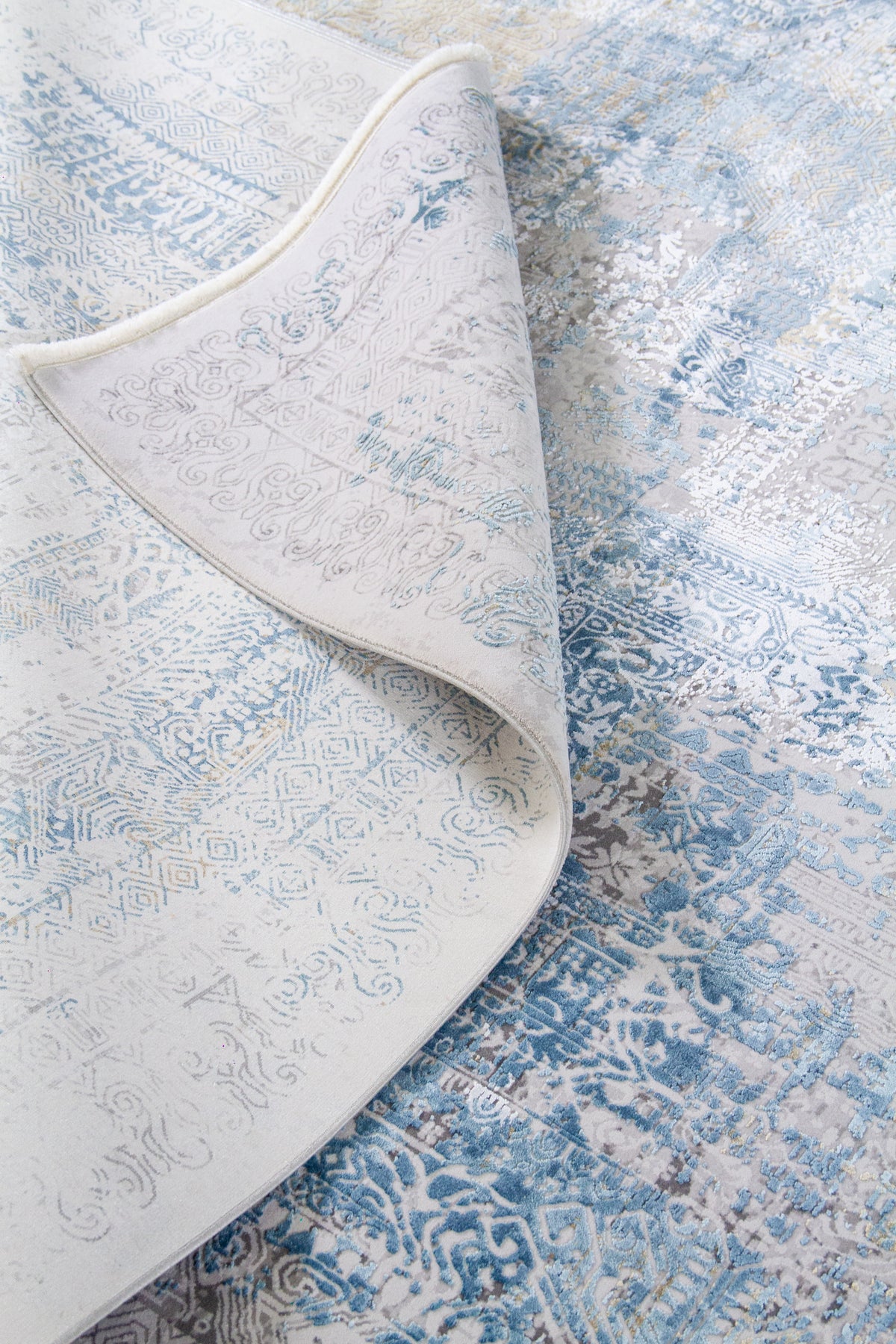 Detalle del reverso y textura de alfombra rectangular con diseño abstracto desgastado