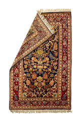 Alfombra oriental con una esquina doblada que muestra el reverso tejido y destaca la riqueza de los colores: azul, dorado, rojo y beige.
