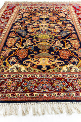 Perspectiva baja de una alfombra oriental, enfocando el centro del diseño con un gran jarrón amarillo y ramas florales sobre un fondo azul profundo.