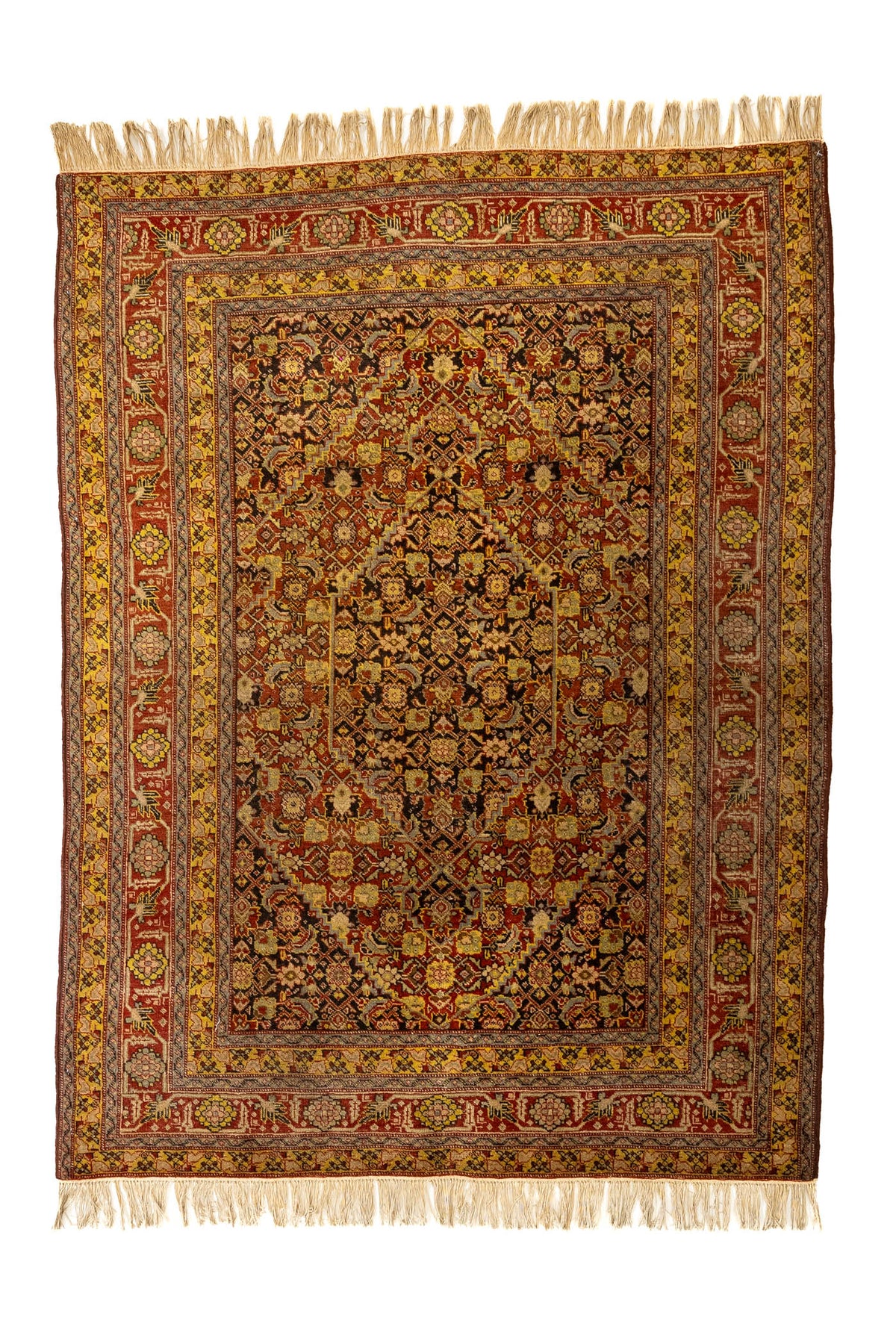Vista completa superior de una alfombra oriental con fondo oscuro, decoración geométrica intrincada en tonos rojo, mostaza y negro, rodeada de múltiples bordes ornamentados.