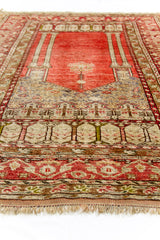 Vista lateral baja de la alfombra, centrada en la sección del mihrab y las columnas, con ornamentación superior en grisáceo.