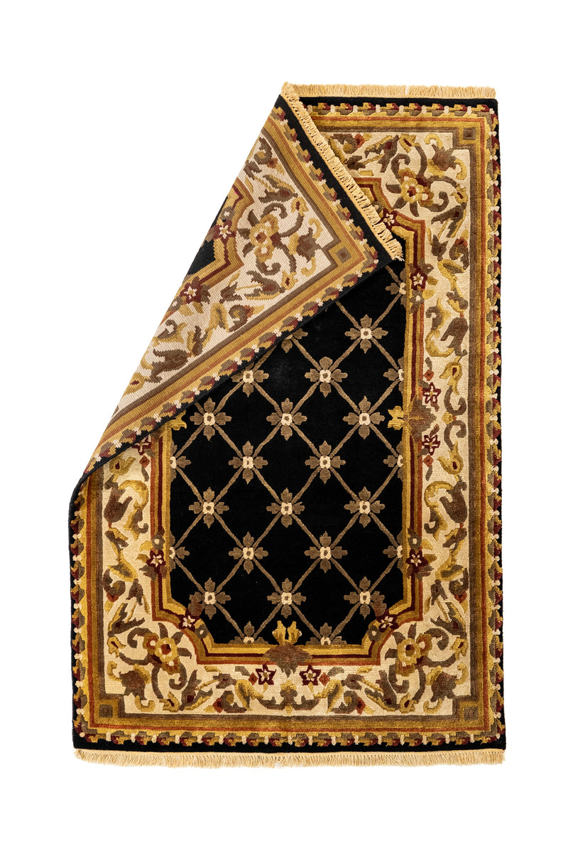 Alfombra vista desde arriba con una esquina doblada, mostrando el reverso y el diseño simétrico de inspiración europea con tonos sobrios y elegantes.