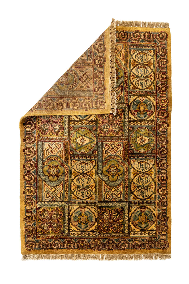 Alfombra doblada desde una esquina para mostrar el reverso, con detalles de los patrones en tonos tierra y contrastes de diseño simétrico.