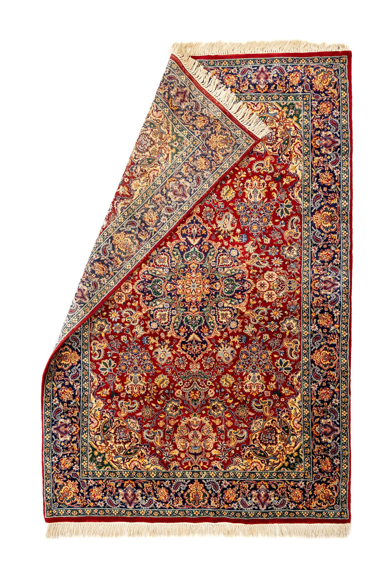 Alfombra con una esquina doblada mostrando el reverso y los nudos del tejido artesanal.