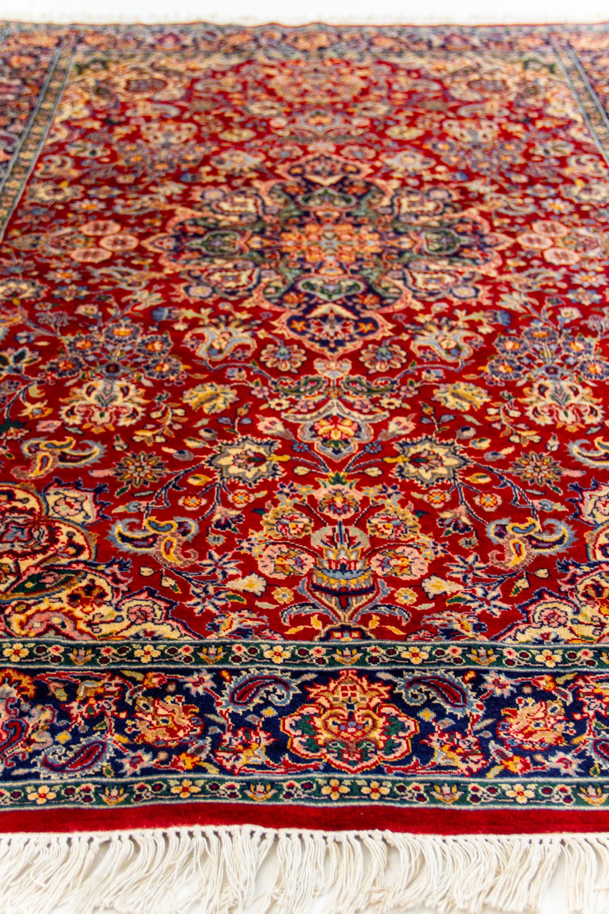 Vista en perspectiva baja de la alfombra, destacando el patrón simétrico y la textura del tejido.