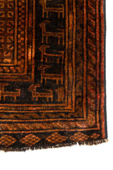 Vista cercana de la esquina de la alfombra oriental con diseño de figuras animales en el borde inferior y patrón tribal.