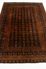 Vista en perspectiva baja de la alfombra oriental resaltando el patrón repetitivo en tonos marrón oscuro y negro.
