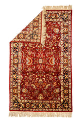Vista superior de alfombra parcialmente doblada, mostrando el reverso y la densidad del tejido artesanal.