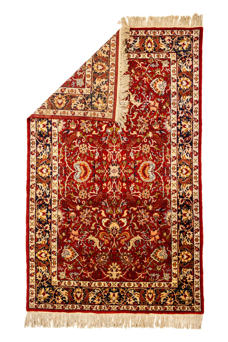 Vista superior de alfombra parcialmente doblada, mostrando el reverso y la densidad del tejido artesanal.