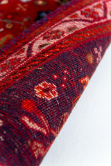 Detalle del reverso de la alfombra persa enrollada, destacando la calidad del tejido y los colores intensos del hilo.