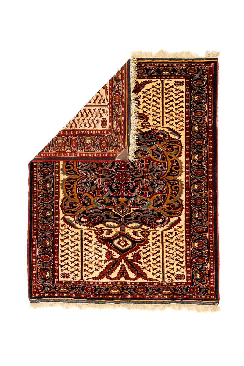 Alfombra con una esquina doblada mostrando el reverso tejido y el patrón central detallado en vista superior.