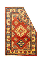 Alfombra con una esquina doblada mostrando el reverso y los detalles simétricos de su diseño tradicional.