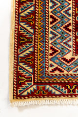 Detalle de la esquina inferior izquierda de la alfombra, mostrando el acabado de los bordes, las franjas y la textura del tejido.