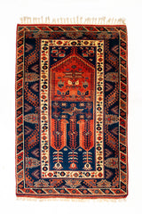 Vista superior completa de una alfombra oriental con un diseño simétrico y un tono predominante rojo, enmarcada por patrones tribales.