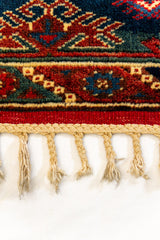 Primer plano de los flecos inferiores y la textura de la alfombra, con enfoque en los detalles del nudo y la terminación del borde.