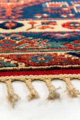 Imagen en ángulo bajo resaltando la superficie de la alfombra, donde se aprecia el relieve del tejido y los detalles en azul y rojo.