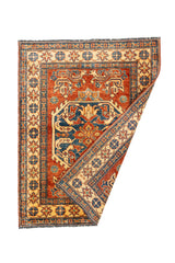 Alfombra oriental parcialmente doblada que revela el reverso tejido, mostrando la calidad artesanal y los colores vibrantes del diseño.