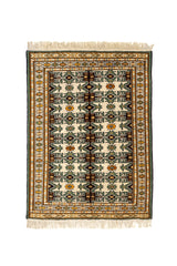 Alfombra oriental de fondo crema con patrón geométrico en verde, negro, dorado y detalles florales simétricos.