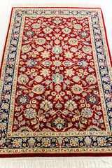 Vista en perspectiva de la alfombra roja destacando los detalles florales y el entramado central dorado y beige.
