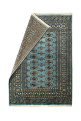 Alfombra Bukhara parcialmente doblada, mostrando la parte posterior tejida a mano y los detalles precisos del borde decorativo.