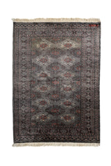 Vista superior de alfombra oriental con patrón geométrico repetitivo en tonos gris, rojo y marfil, con flecos en los extremos.