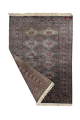 Alfombra oriental parcialmente doblada mostrando el reverso, destacando su diseño artesanal simétrico.